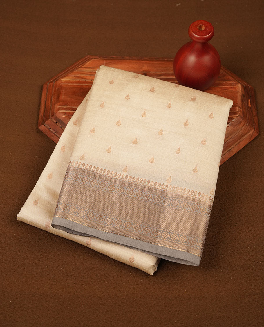 Cream colour tussar saree featuring litte gold zari motifs on body, contrast grey colour border and pallu with zari woven design, comes with matching blouse piece.