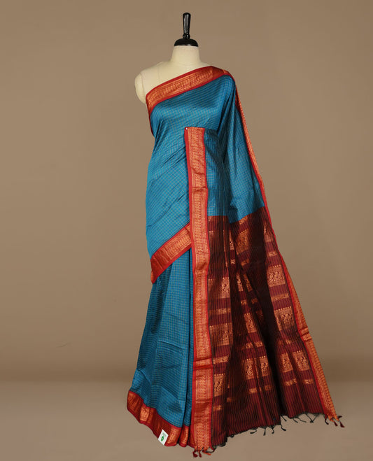 Blue colour kalyani cotton saree featuring gold zari check pattern on body, complemented by Maroon colour with Antique zari border, paired with matching blouse piece.