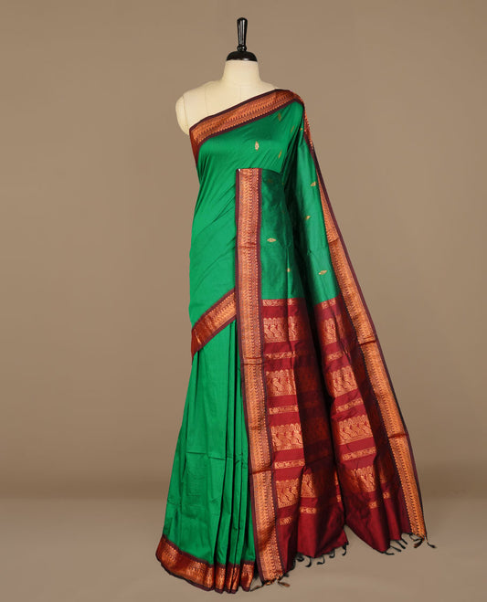 Green colour kalyani cotton saree featuring antique zari motifs on body, complemented by Maroon colour with Antique zari border, paired with matching blouse piece.