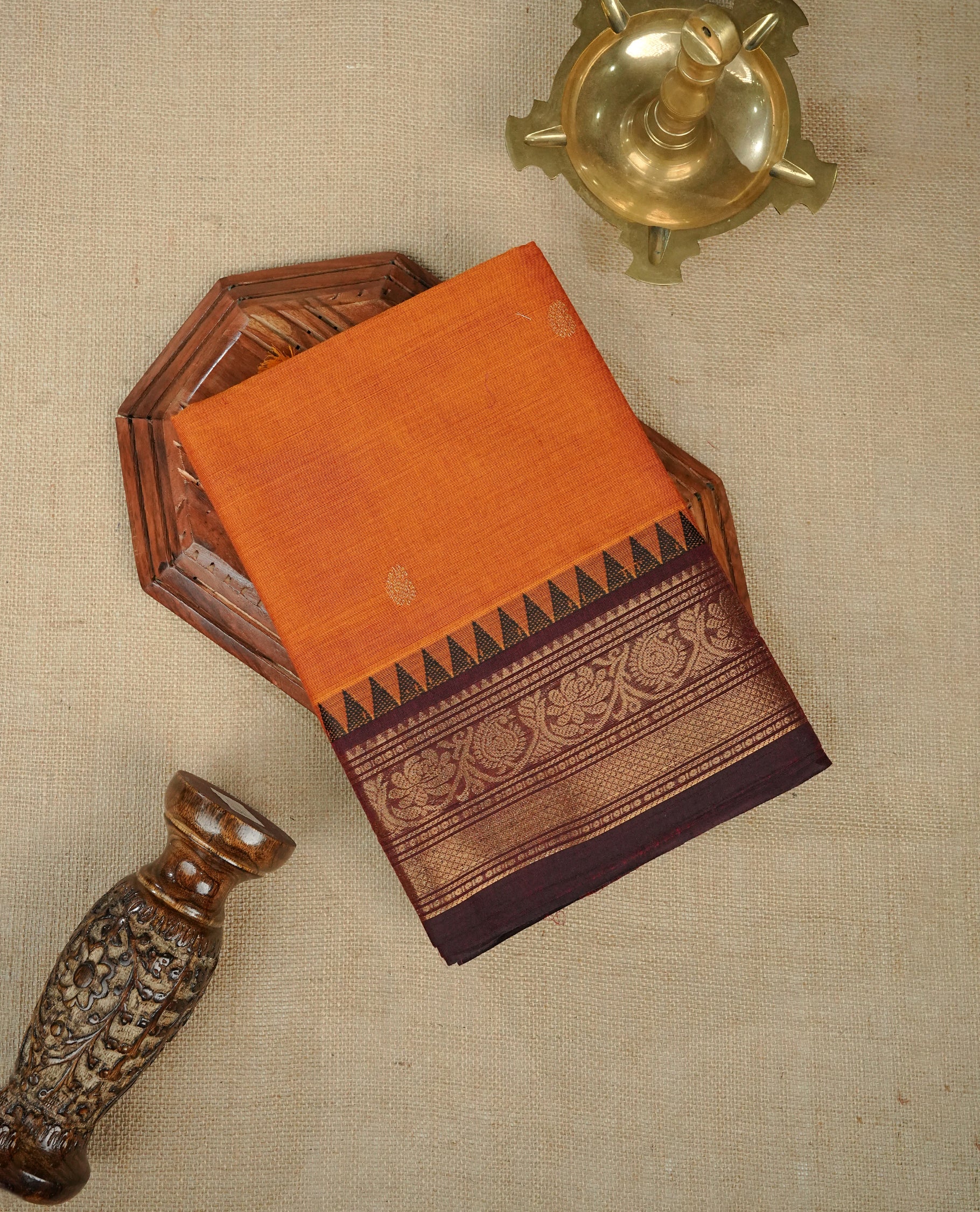 Orange colour chettinad cotton saree featuring Elegant plain body, complemented by contrast Brown colour with gold zari border, comes with matching blouse piece.