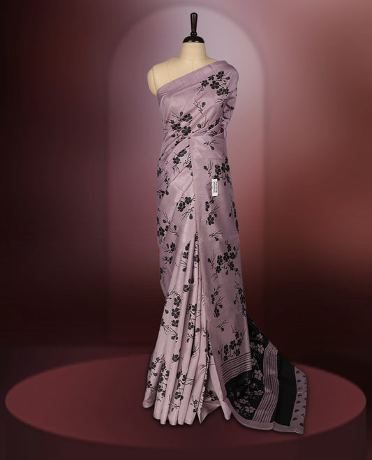 Pastel purple colour saree with delicate black floral prints spread across the body, The black pallu features coordinated floral motifs and stripes, Finished with a sleek border and paired with a matching blouse.