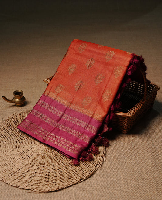 Rust orange colour pure tussar Banaras silk saree featuring elegant gold zari motifs across the body, complemented by a contrast red border with rich zari detailing. Comes with a matching blouse piece