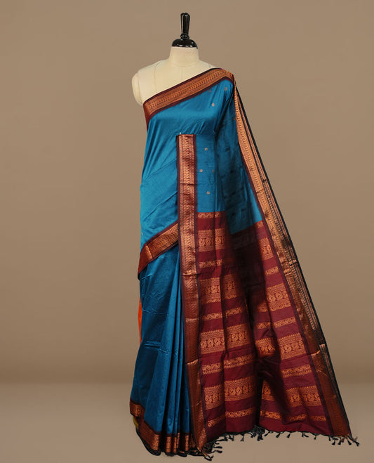 Blue colour kalyani cotton saree featuring antique zari motifs on body, complemented by Maroon colour with Antique zari border, paired with matching blouse piece.