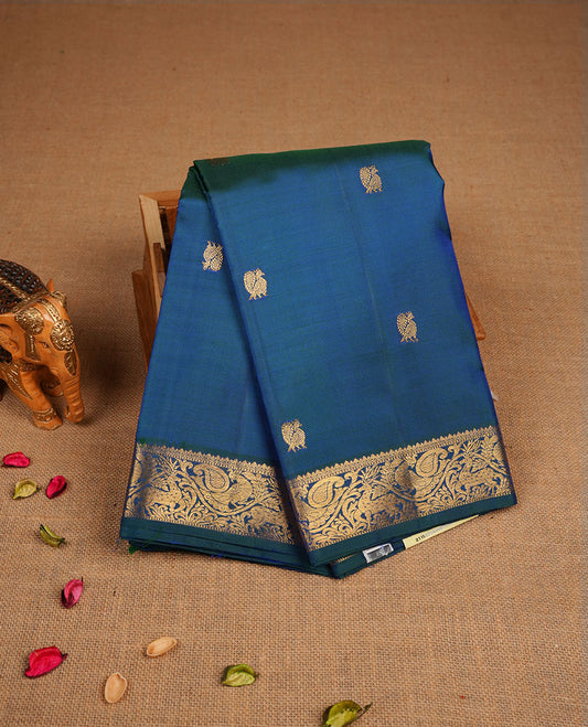 Peacock blue pure traditional Kancheepuram silk saree adorned with gold zari peacock motifs across the body, featuring elegant traditional borders with animal motifs, beautifully paired with a matching blouse piece.