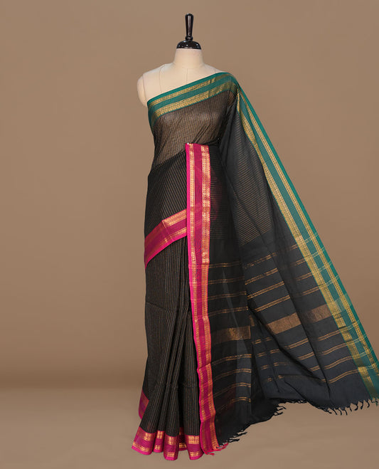 Black colour chettinad cotton featuring gold zari check pattern on body , complemented by contrast teal & magenta double colour with gold zari border, paired with matching blouse piece.