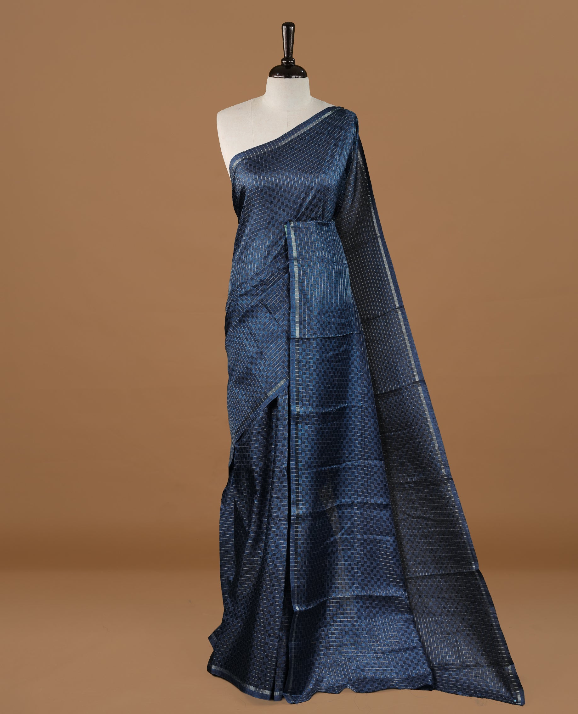 Navy Blue colour Semi Tussar saree featuring an elegant zari fancy check pattern on the body, highlighted with a small border for a refined look. Comes without a blouse piece.