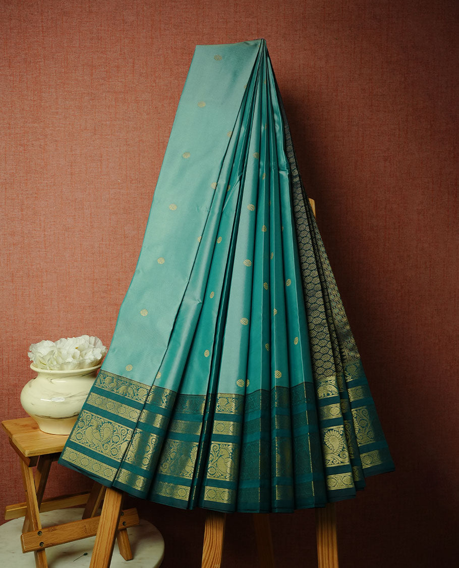 Aqua colour soft silk saree featuring gold zari motifs on body, complemented by contrast Teal colour with zari border, paired with matching blouse piece.