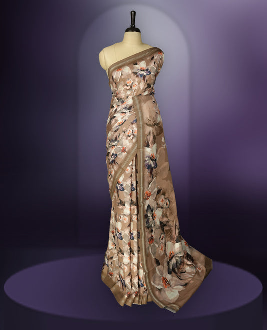 Pastel brown colour saree adorned with elegant floral prints on the body, enhanced with a subtle matching border, complemented by a beautifully printed pallu featuring blooming flowers, and paired with a matching blouse.