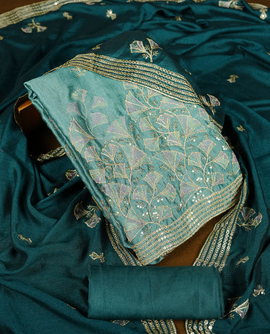pastel teal colour olive colour churidar material with subtle mirror and thread embroidery, finished with delicate border detailing and paired with a matching plain bottom and dupatta.