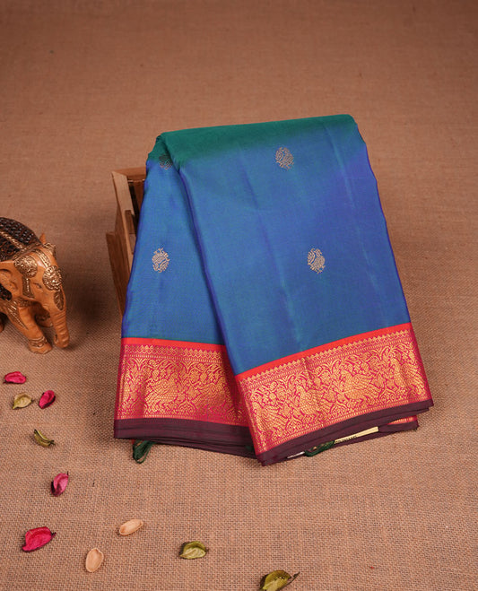 Peacock Blue colour pure traditional Kancheepuram silk saree adorned with gold zari peacock motifs across the body, featuring elegant contrast Pink traditional borders, beautifully paired with a matching blouse piece.