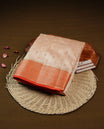 Light Gold Tussar saree featuring Gold zari buttas on body, complemented by contrast orange Colour with Gold zari border, comes with matching blouse piece.
