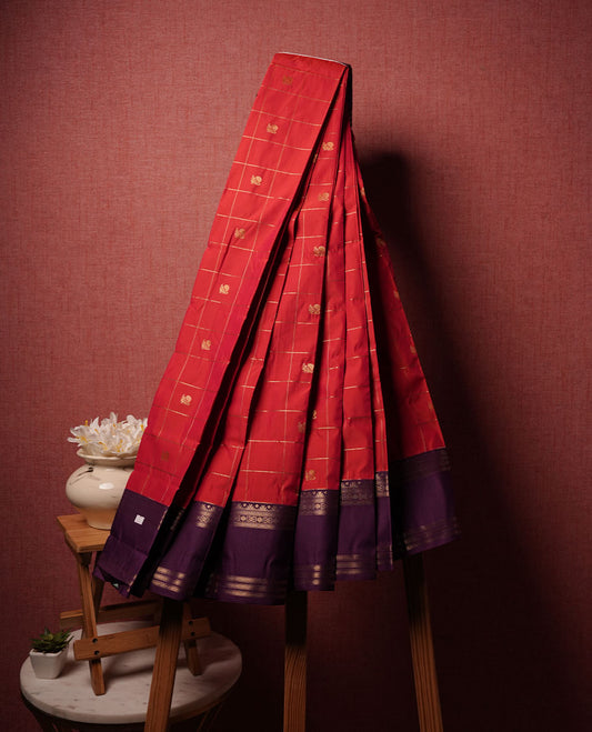 Red colour semi silk saree highlighting gold zari box pattern  and motifs across body, featuring contrast purple colour border with gold zari pattern, comes with matching blouse .
