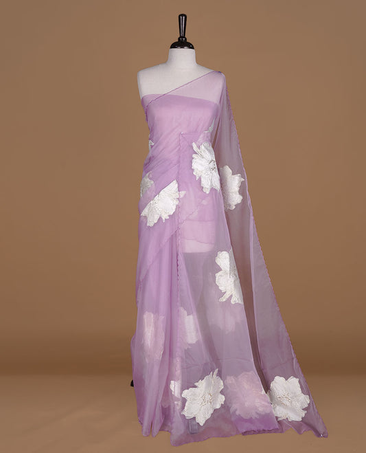 Lavender colour semi organza saree featuring white floral & gold thread pattern, highlighting scalp design border, paired with matching blouse piece.