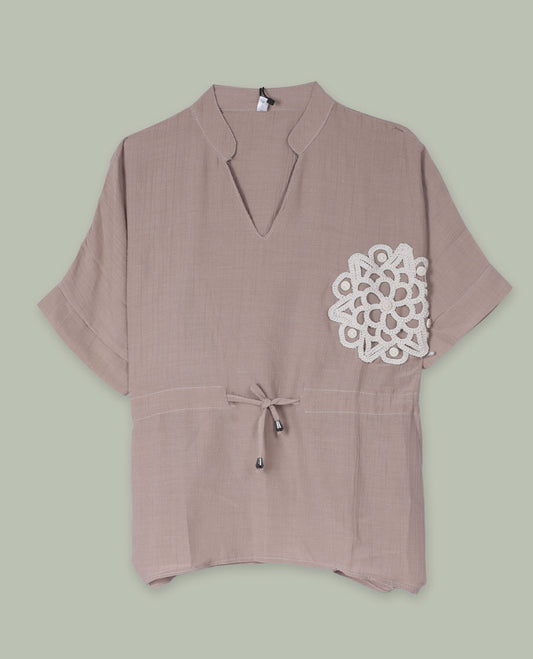Taupe short-sleeve top with V-slit band neckline, contrast white crochet motif on one side, and adjustable drawstring detail at the waist