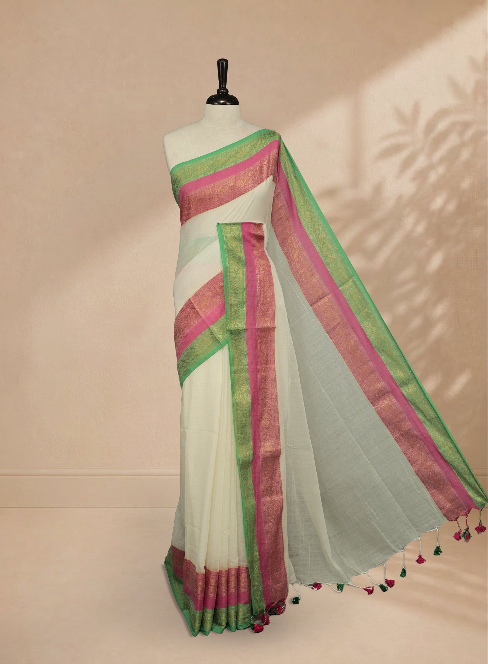 Off white Colour Mul Cotton saree featuring Elegant plain body, contrast Green & Pink colour with gold zari traditional border.