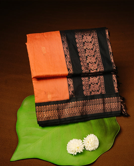Orange colour kalyani cotton saree featuring gold zari motifs on body, highlighting contrast Black colour with Antique gold zari border, paired with matching blouse piece.