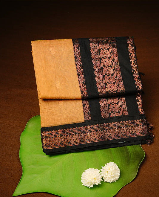 Mustard colour kalyani cotton saree featuring gold zari motifs on body, highlighting contrast Black colour with Antique gold zari border, paired with matching blouse piece.