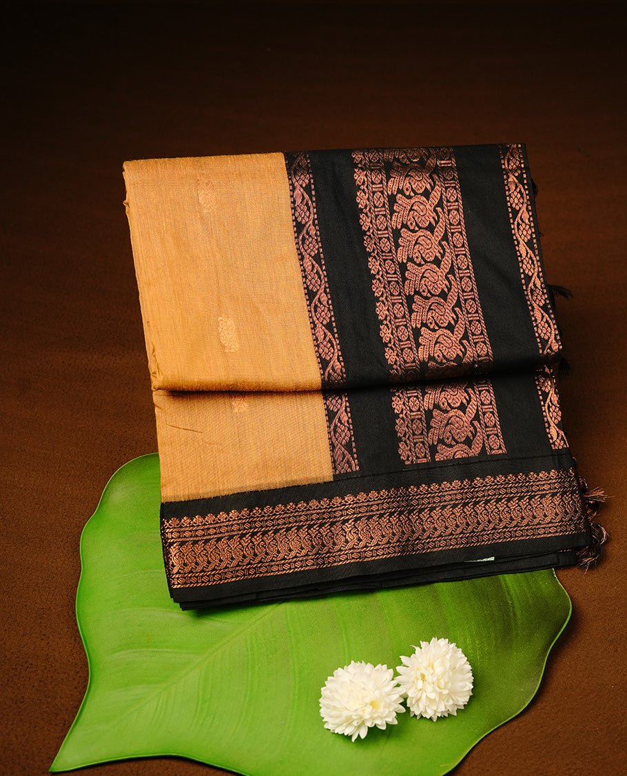 Mustard colour kalyani cotton saree featuring gold zari motifs on body, highlighting contrast Black colour with Antique gold zari border, paired with matching blouse piece.