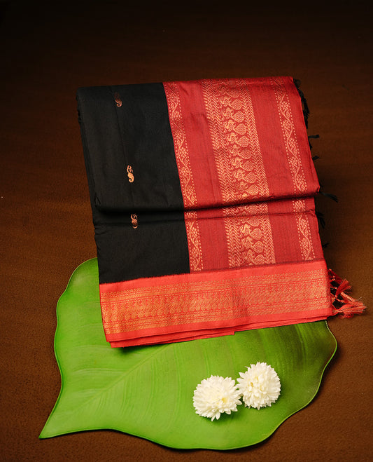 Black colour kalyani cotton saree featuring gold zari motifs on body, highlighting contrast Maroon colour with Antique gold zari border, paired with matching blouse piece.