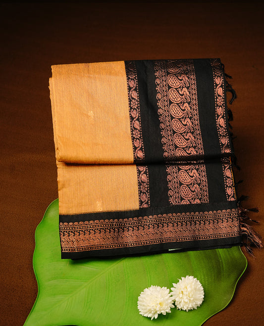 Mustard colour kalyani cotton saree featuring gold zari motifs on body, highlighting contrast Black colour with Antique gold zari border, paired with matching blouse piece.