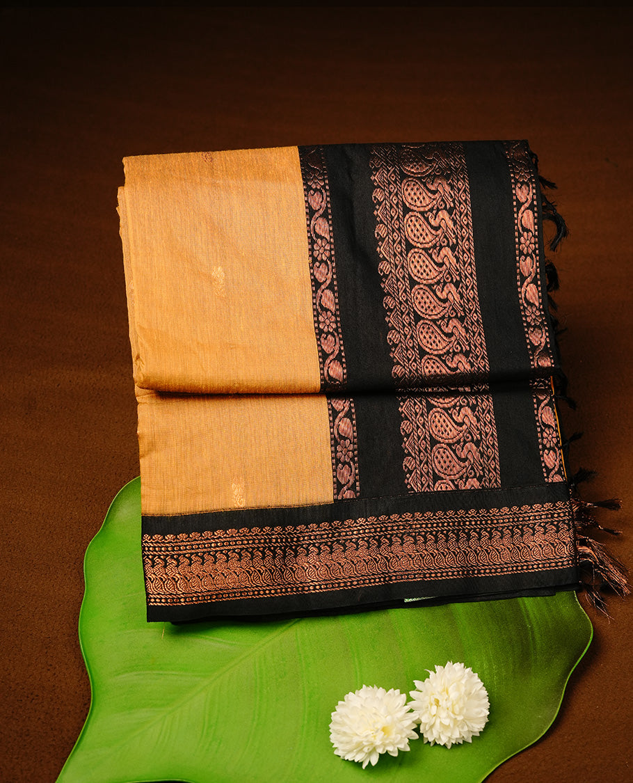 Mustard colour kalyani cotton saree featuring gold zari motifs on body, highlighting contrast Black colour with Antique gold zari border, paired with matching blouse piece.