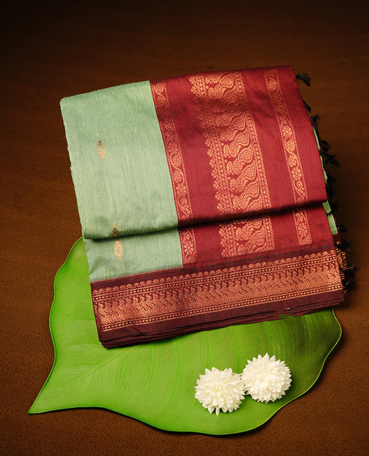 Pista green colour kalyani cotton saree featuring gold zari motifs on body, highlighting contrast Maroon colour with Antique gold zari border, paired with matching blouse piece.