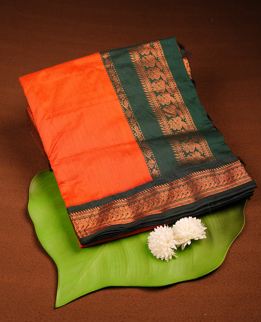 Rust orange colour Kalyani cotton saree featuring a plain elegant body, complemented by a rich dark green zari border and traditional woven pallu, paired with a matching blouse.