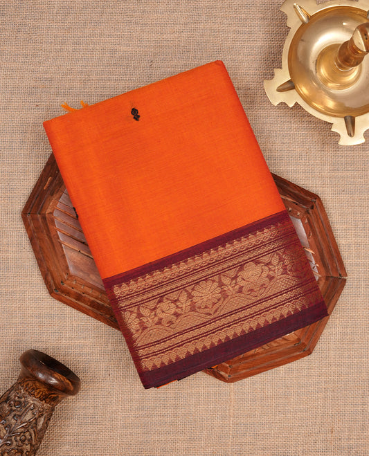 Orange colour chettinad cotton featuring black thread motifs on body, complemented by contrast brown colour with gold zari border, paired with matching blouse piece.
