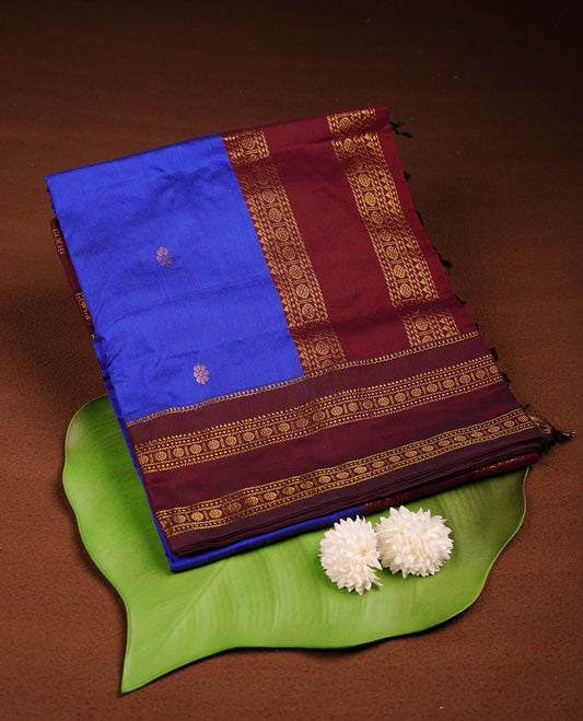 Royal blue colour saree with subtle zari motifs, complemented by a rich maroon zari border and traditional pallu, paired with a matching blouse.