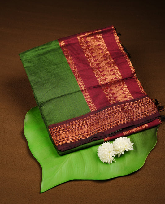Green colour Kalyani cotton saree featuring a plain elegant body, complemented by a deep maroon border and traditional woven pallu, paired with a matching blouse.