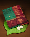 Dark Green colour mixed Kalyani cotton saree with zari motifs on the body, maroon zari border and traditional elephant motif pallu, paired with a matching blouse.