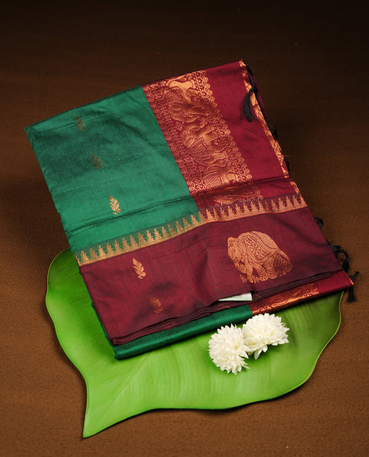 Dark Green colour mixed Kalyani cotton saree with zari motifs on the body, maroon zari border and traditional elephant motif pallu, paired with a matching blouse.