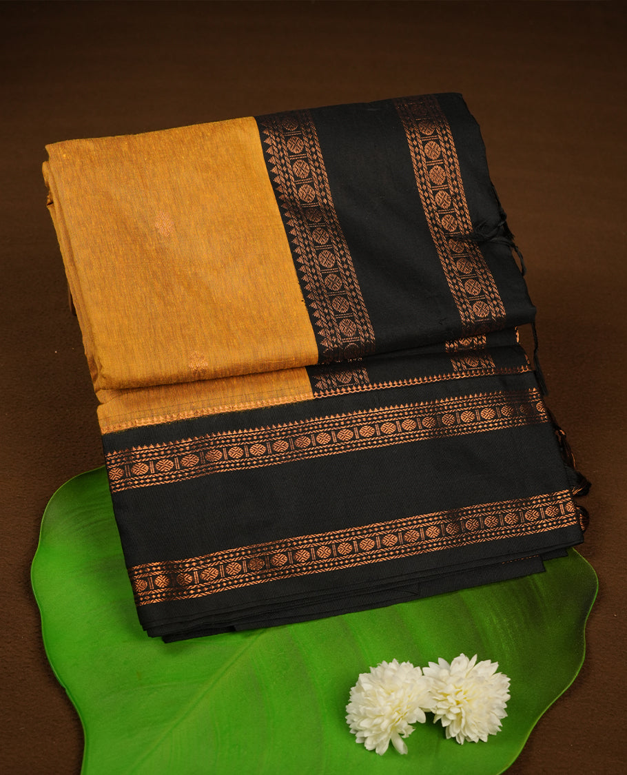 Mustard colour kalyani cotton saree featuring Antique zari motifs on body, contrast Black colour border with floral and chakra antique zari pattern, paired with matching blouse piece.