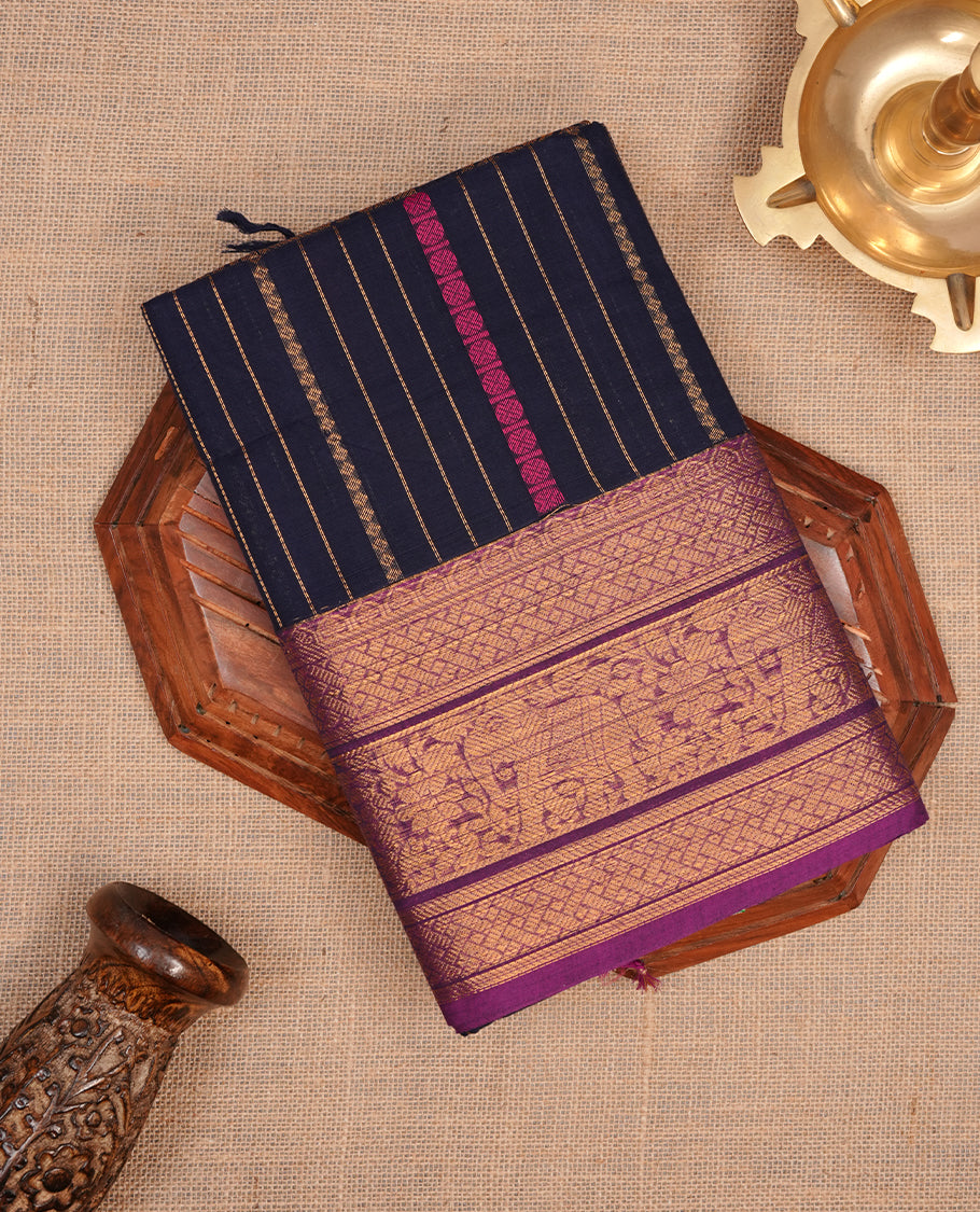 Navy blue colour chettinad saree featuring gold zari stripes on body, complemented by contrast Purple colour with traditional border, paired with matching blouse piece.
