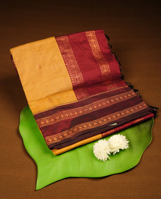 Mustard colour mixed Kalyani cotton saree with subtle zari motifs, maroon zari border and rich traditional pallu, paired with a matching blouse.