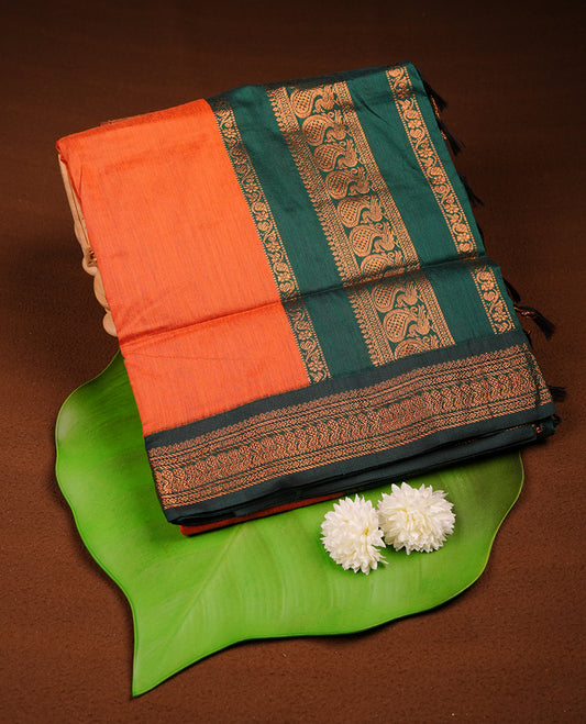 Rust orange colour Kalyani cotton saree featuring a plain elegant body, complemented by a rich green zari border and traditional woven pallu, paired with a matching blouse.