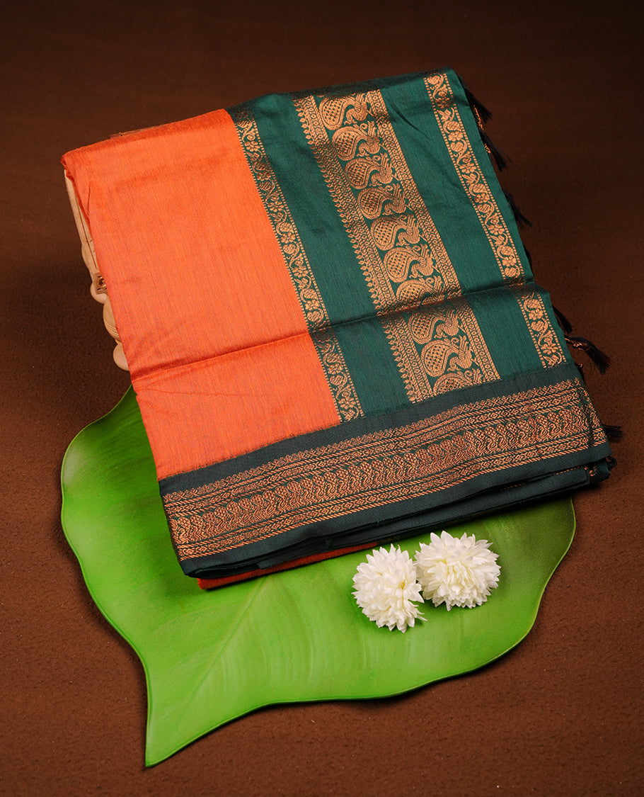 Rust orange colour Kalyani cotton saree featuring a plain elegant body, complemented by a rich green zari border and traditional woven pallu, paired with a matching blouse.