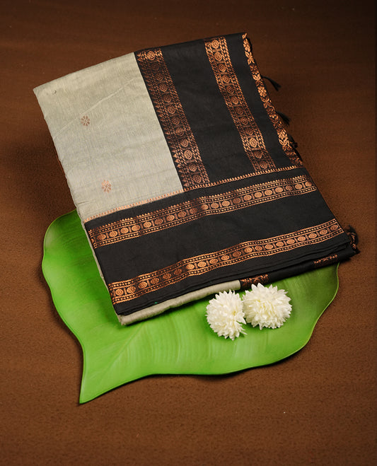 Grey colour Kalyani cotton saree featuring a plain elegant body, complemented by a black zari border and traditional woven pallu, paired with a matching blouse.