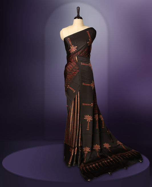 Black colour saree beautifully embellished with brick red woven palm tree and geometric motifs, featuring a rich patterned border and pallu, paired with a matching blouse.