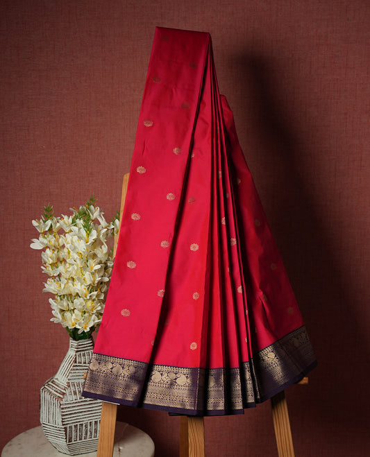 Dark pink colour Semi Silk Saree with gold zari motifs on the body, paired with a contrasting dark purple traditional pallu and border featuring peacock motifs, and completed with a matching blouse piece.