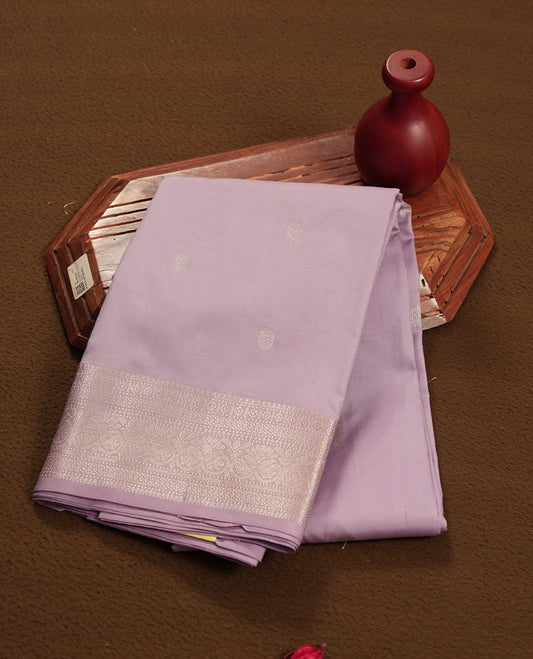 Lavender colour semi soft silk saree featuring a golden textured patterned body, complemented by self coloured golden traditional motifes on pallu & border and a matching blouse piece.