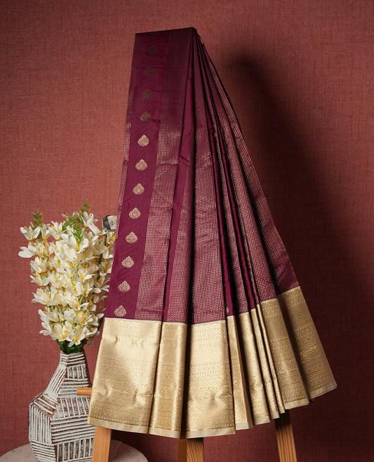 Burgundy colour Semi Silk Saree with gold zari striped patterns on the body, paired with a contrasting cream colour traditional pallu and border, and a matching blouse piece.