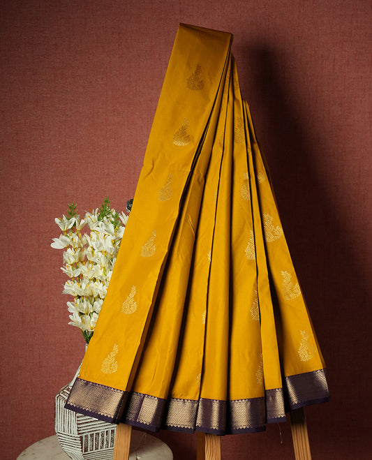 Gold yellow colour Semi Silk Saree with gold zari patterns on the body, paired with a contrasting dark violet colour traditional pallu and border, and a matching blouse piece.