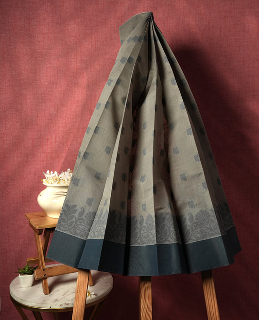 Grey colour silk cotton saree featuring elegant floral zari motifs on the body, complemented by a rich contrast border and pallu with traditional woven detailing & Comes with a matching blouse piece.