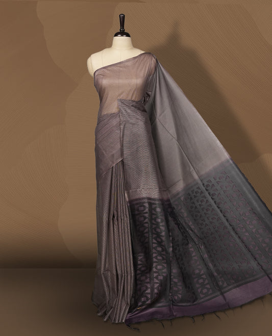 Grey brown colour semi jute saree featuring fine striped body work for a subtle texture, Accented with a geometric woven purple shaded pallu, sleek border, soft drape, and a matching blouse piece for a complete look.