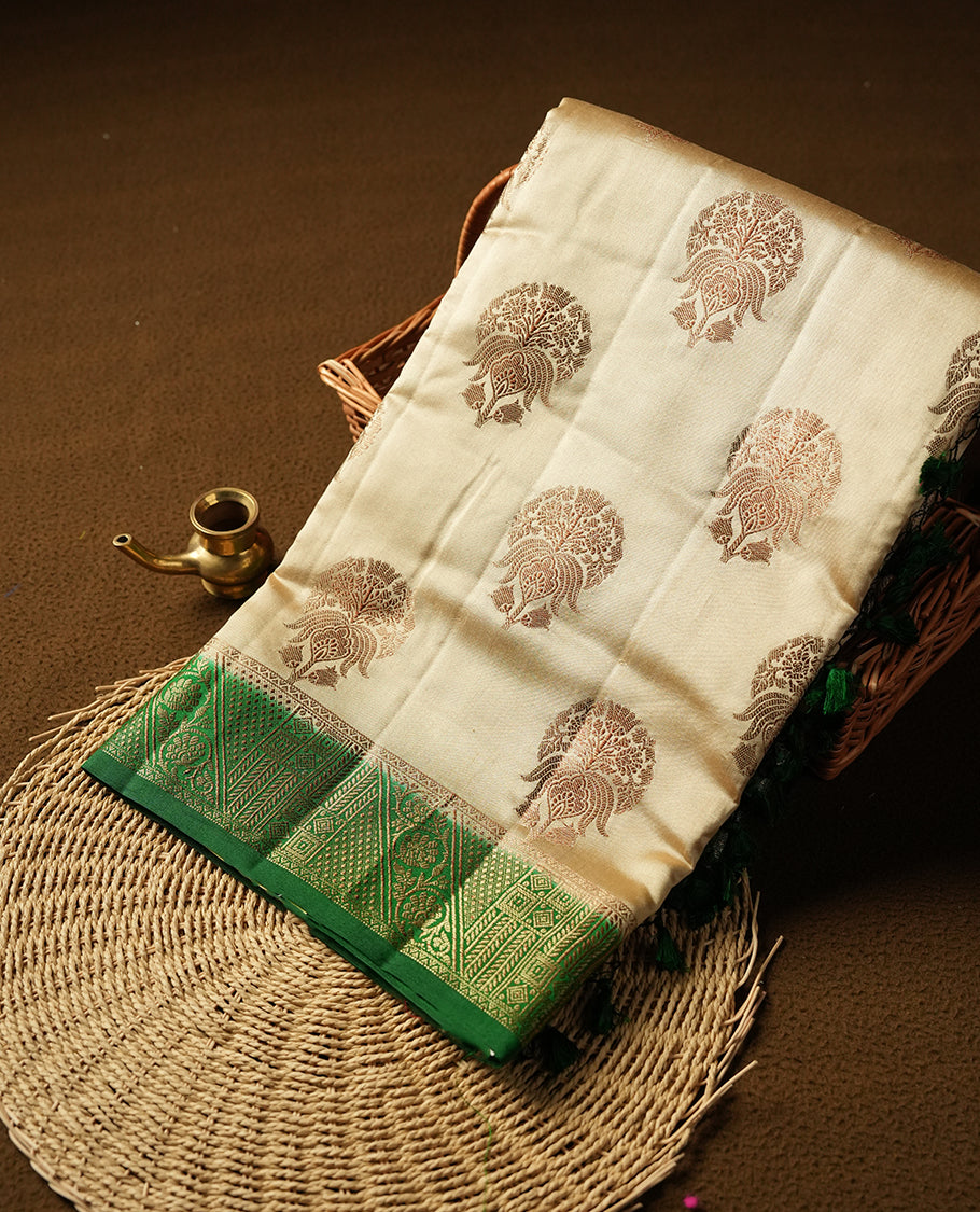 Cream beige Banaras soft silk saree with gold zari oval motifs on body, with contrast green colour floral pattern on pallu, border, and Matching blouse.