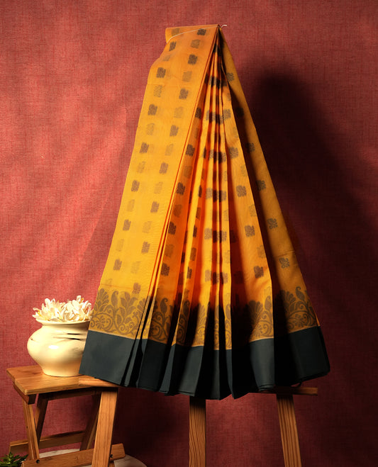 Saffron orange colour silk cotton saree featuring elegant grey floral and geometric woven motifs across the body, paired with a deep contrast grey border and pallu showcasing intricate traditional patterns & Comes with a matching blouse piece.