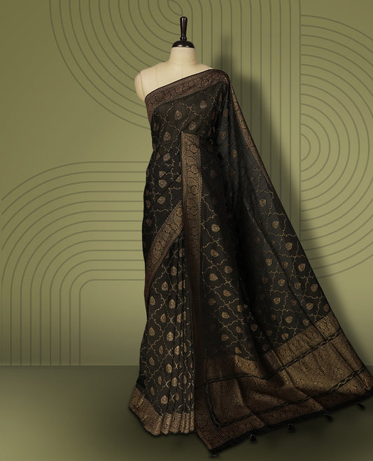 Black colour semi Banarasi Tussar Georgette saree with gold zari motifs on the body, a grand woven golden pallu, and ornate zari border, Includes a matching blouse piece for a complete look.