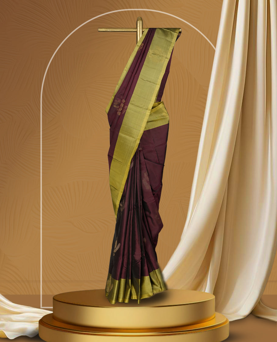 Maroon colour soft silk saree adorned with small golden buttas, enhanced by a shimmering light olive green zari border and pallu with delicate motifs & paired with a matching blouse.