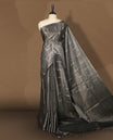 Grey colour semi jute tissue saree accentuated with subtle dotted motifs across the body, The saree features a finely woven pallu and sleek borders, adding a touch of understated elegance & Comes with a matching blouse piece.